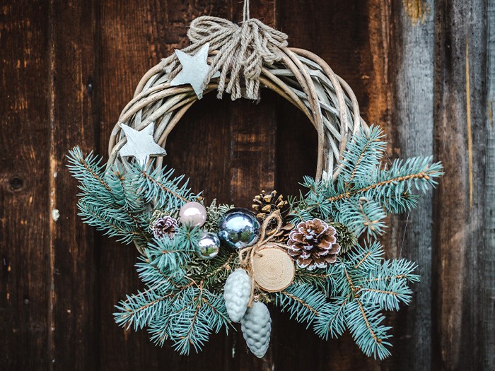 A pine wreath hanging on a wooden front door.