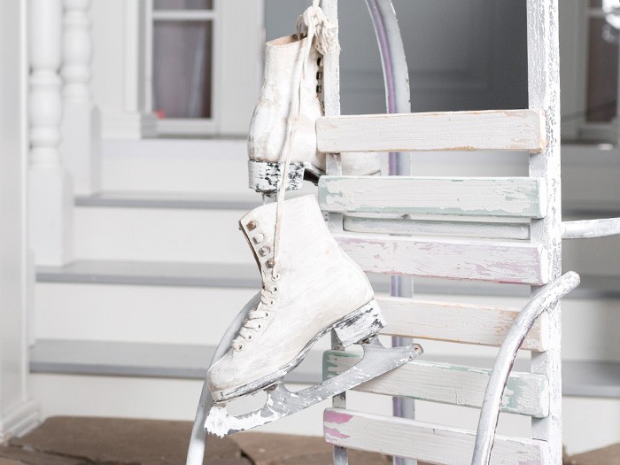 A pair of old ice skates hanging on an old wooden sled.